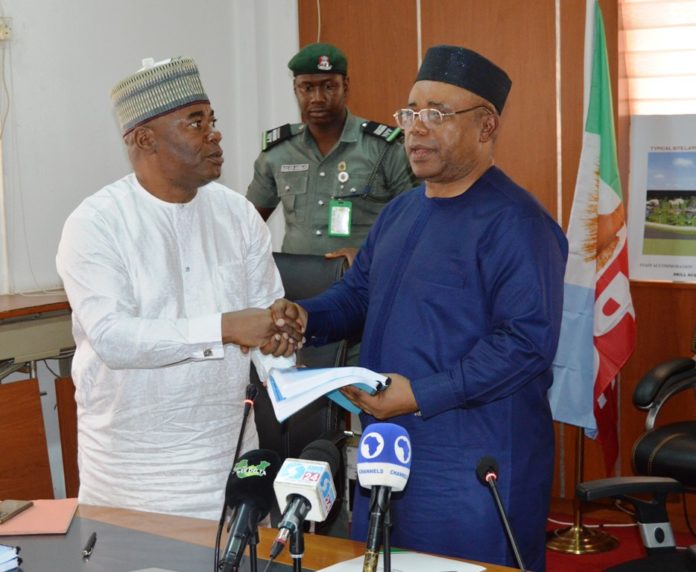 L-R, The Permanent Secretary, MNDA, Engr. Olufunso Olusesan FNSE handing over working document to the Hon. Minister, MNDA, Umana Okon Umana.