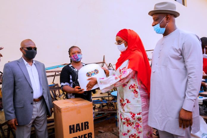 WhatsApp Image 2020-06-02 at 8.32.43 PM (2nd right) Honourable Minister of Humanitarian Affairs Disaster Management and Social Development, Sadiya Umar Farouq, giving relief materials to one of the victims of the Ogbeogonogo market fire during the flag off for the distribution of the relief items for reconstruction and development of new shops at the market in Delta State