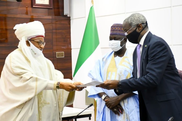 Chairman Niger Council of Traditional Rulers & the Etsu of Nupe ,His Royal Highness, Dr. Yahaya Abubakar handing over his presentation to Honourable Minister of Works and Housing , Babatunde Raji Fashola and Honourable Minister of State for Works and Housing , Abukar D Aliyu during his courtesy visit to the Ministry of Works and Housing Headquarters in Abuja