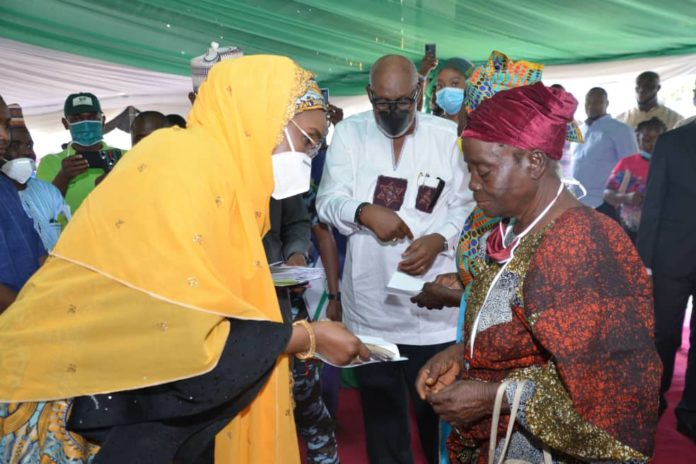 FMHADMSD ONDO (left) Honourable Minister of Humanitarian Affairs, Disaster Management and Social Development, Sadiya Umar Farouq, the Executive Governor of Ondo State, Arakunrin Oluwarotimi Akeredolu, presenting Federal Government Special Cash Grant for Rural Women Programme to a beneficiary, during the flag off ceremony of the programme in Akure, Ondo State, 26th November, 2020. Photo by Khalid Ahmed