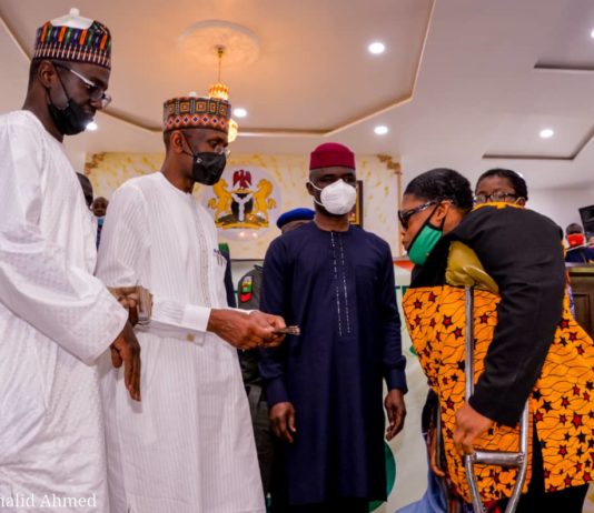 (2nd Left) The Representative of the Honourable Minister of Humanitarian Affairs, Disaster management and Social Development, The Permanent Secretary of the Ministry, Bashir Nura Alkali, (2nd Right) the Representative of the Abia State Governor, the Deputy Governor of the State, Hon. Sir, Ude Oko Chukwu, (1st Leftt) Director Humanitarian Affairs, Grema Ali Alhaji, (1st Right) a Beneficiary of the Grant, a woman with disability, Nnaji Uroma, during the disbursement of the Federal Government cash Grant for Rural Women in Abia State, on 5th March, 2021
