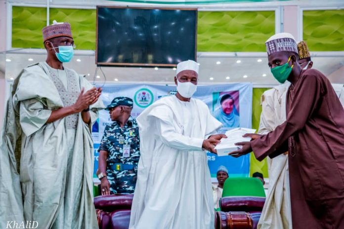 (Left) The Representative of the Honourable Minster of Humanitarian Affairs, Disaster Management and Social Development,Sadiya Umar Farouq, the Permanent Secretary of the Ministry, Bashir Nura Alkali, (middle) The Representative of the Government of Kano State, SSG Usman Waziru Gaya, (Right) an Independent Monitor, during the distribution of engagement letters and monitoring devices to Independent Monitors in Kano State, on the 15th June, 2021. In Kano.
