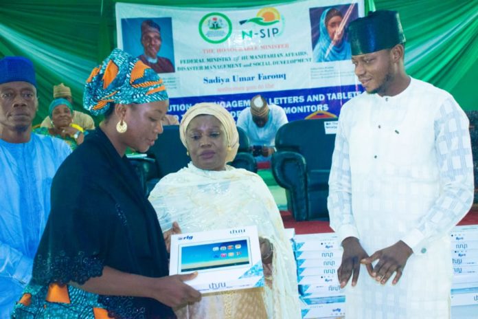 IMG-20210630-WA0000 (middle) Representative of the Honourable Minister of Humanitarian Affairs, Disaster Management and Social Development, Sadiya Umar Farouq, the Deputy Director, Planning, Research and Statistics of the Ministry, Safiya Sani, (Right) Kogi State Focal Person on NSIP, Abdulkareem Suleiman, presenting engagement letter and tablet to (left) trained Independent Monitor, Mummy Rekiya Mohammed, during the flag off ceremony of the distribution of engagement letters and tablets to trained Independent Monitors in Kogi State, Wednesday June 30th, 2021