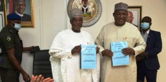 Outgoing and Incoming Permanent Secretaries exchanging documents at the Handing Over Ceremony
