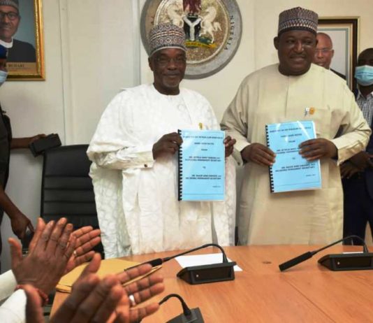 Outgoing and Incoming Permanent Secretaries exchanging documents at the Handing Over Ceremony