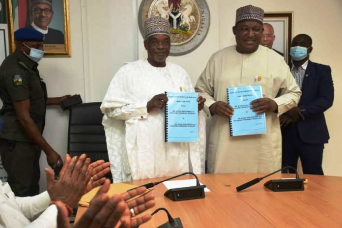 Outgoing and Incoming Permanent Secretaries exchanging documents at the Handing Over Ceremony