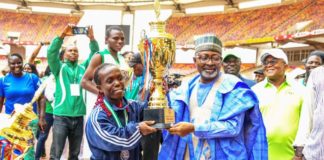 Representative of the Hon. Minister of Youth and Sports Development, Mr Sunday Dare presenting trophy to Tram Bayelsa, winner of the maiden edition of 2022 Para Games in Abuja.