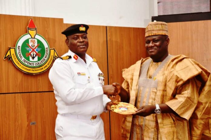 The Permanent Secretary, MOD, Dr. Ibrahim Abubakar Kana, mni receiving a plague from the Commandant of NDC, Rear Admiral O.M. Olotu.
