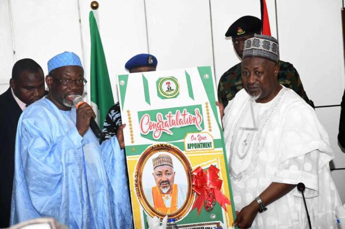 Honourable Minister of Defence, Mohammed Badaru Abubakar CON, mni [R] receiving a congratulatory card from Jigawa State delegation led by Governor Malam Umar Namadi, FCA during the courtesy visit.