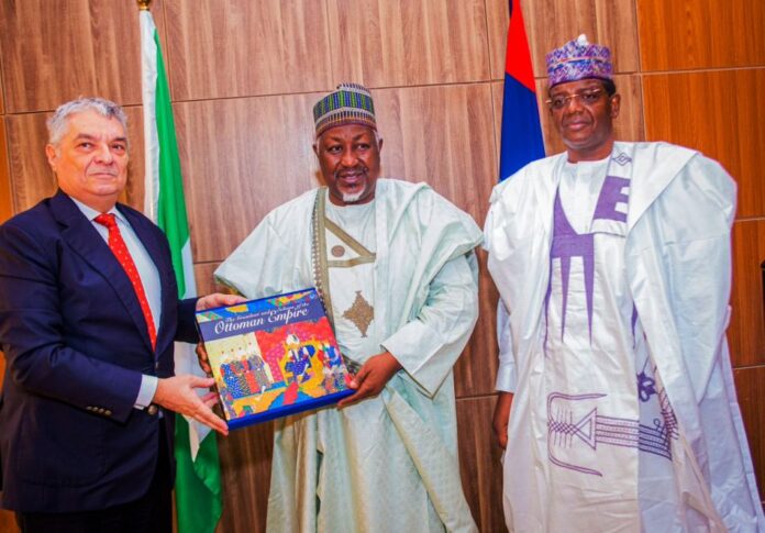 L-R Turkish Ambassador HE Hidayet Bayraktar presenting a souvenir to the Honourable Minister of Defence Mohammed Badaru Abubakar CON mni, with the Honourable Minister of State for Defence, Dr Muhammed Bello Matawalle MON.