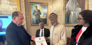 Senior Director, Trade, Oceans and Natural Resources, Paul Kautoke presenting a souvenir to the Minister of Solid Minerals Development, Dr. Oladele Alake. The Permanent Secretary, Dr.Mary Ogbe watches with keen interest.