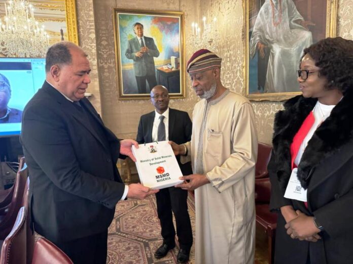 Senior Director, Trade, Oceans and Natural Resources, Paul Kautoke presenting a souvenir to the Minister of Solid Minerals Development, Dr. Oladele Alake. The Permanent Secretary, Dr.Mary Ogbe watches with keen interest.