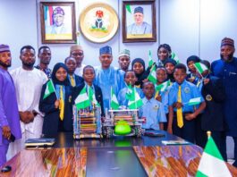 Minister of Information and National Orientation, Mohammed Idris (center), in a group photograph with the students, coaches, and the school's Executive Director, Abba Said (Extreme right)