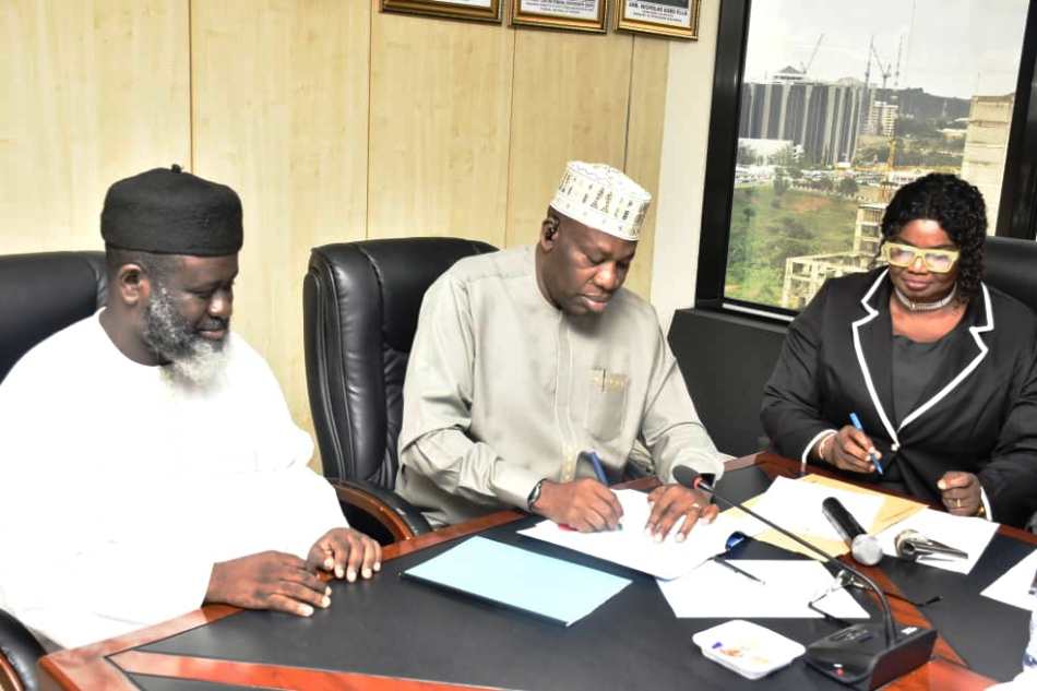 Permanent Secretary, Amb. Nicholas Agbo Ella, signing the agreement documents while Head, Legal Services Department in the Ministry, Mrs. Kate Olusuyi and Chairman, FOSSREA, Mr. Aliyu Hydar Mijinyawa watched on during the signing of agreement ceremony in Abuja