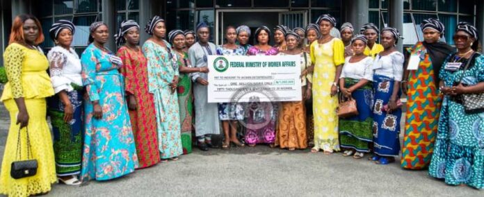 Female Entrepreneurs Representative of the Honourable Minister of Women Affairs/Deputy Director, Women Development Department, Mr. Adamu Web in a pose with the beneficiaries at the Presentation