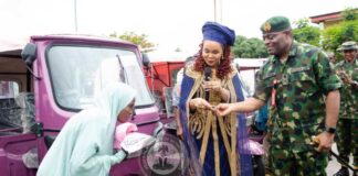 Honourable Minister of Women Affairs presentating the keys, Pink Riders' T-shirt, and cap to one of the beneficiaries. To her left is the Commander, Army Headquarters Garrison, Abuja, Major General Isoni