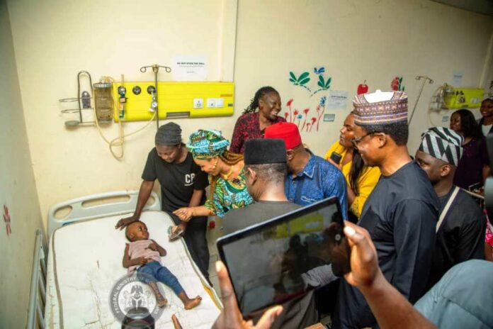 2nd left - Honourable Minister of Women Affairs, Barrister (Mrs) Uju Kennedy-Ohanenye cheering up a little child on admission after making a donation on behalf of the Ministry to his treatment at the National Hospital, Abuja