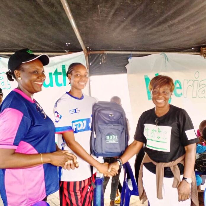 NYG 2024 National Anti Doping Committee R- L: The Project Manager, Anti-Doping for the National Youth Games and the Chief Executive Officer NADC, Ms. Fadeke Fadeyibi, in a handshake with the Pricer Winner,; Jenifer Ehioziobue of Delta State and NADC Official