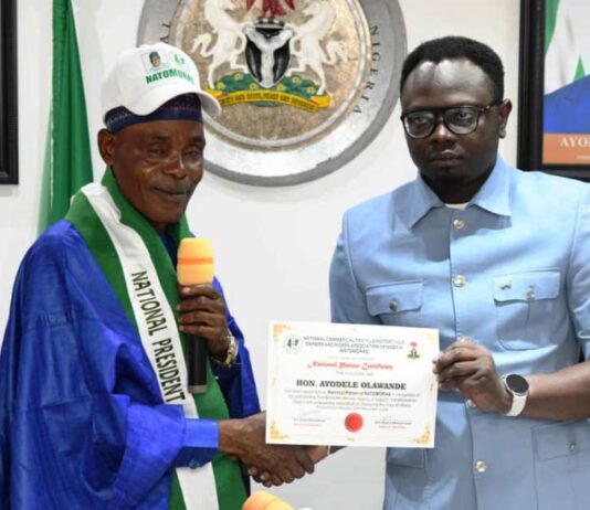 The Honourable Minister, Federal Ministry of Youth Development, Comrade Ayodele Olawande receiving certificate of membership from the National President, NATOMORAS, Ahj. Usman Buba Gwoza, at Abuja.