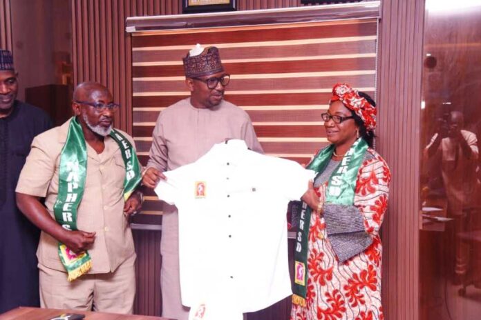 Chairman, National Sports Commission, Mallam Shehu Dikko being presented a uniform by the President of National Association of Physical health Education, Recreation Sports and Dance Prof. Florence Bola Adeyanju (Right) and Dr. Mohammed Sanusi, the National vice president of the Association, when they paid a congratulatory visit to the Chairman in his office, at MKO Abiola National Stadium, Abuja